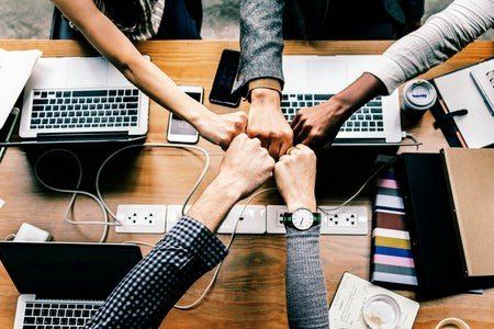 A group of people are putting their hands together on a table.